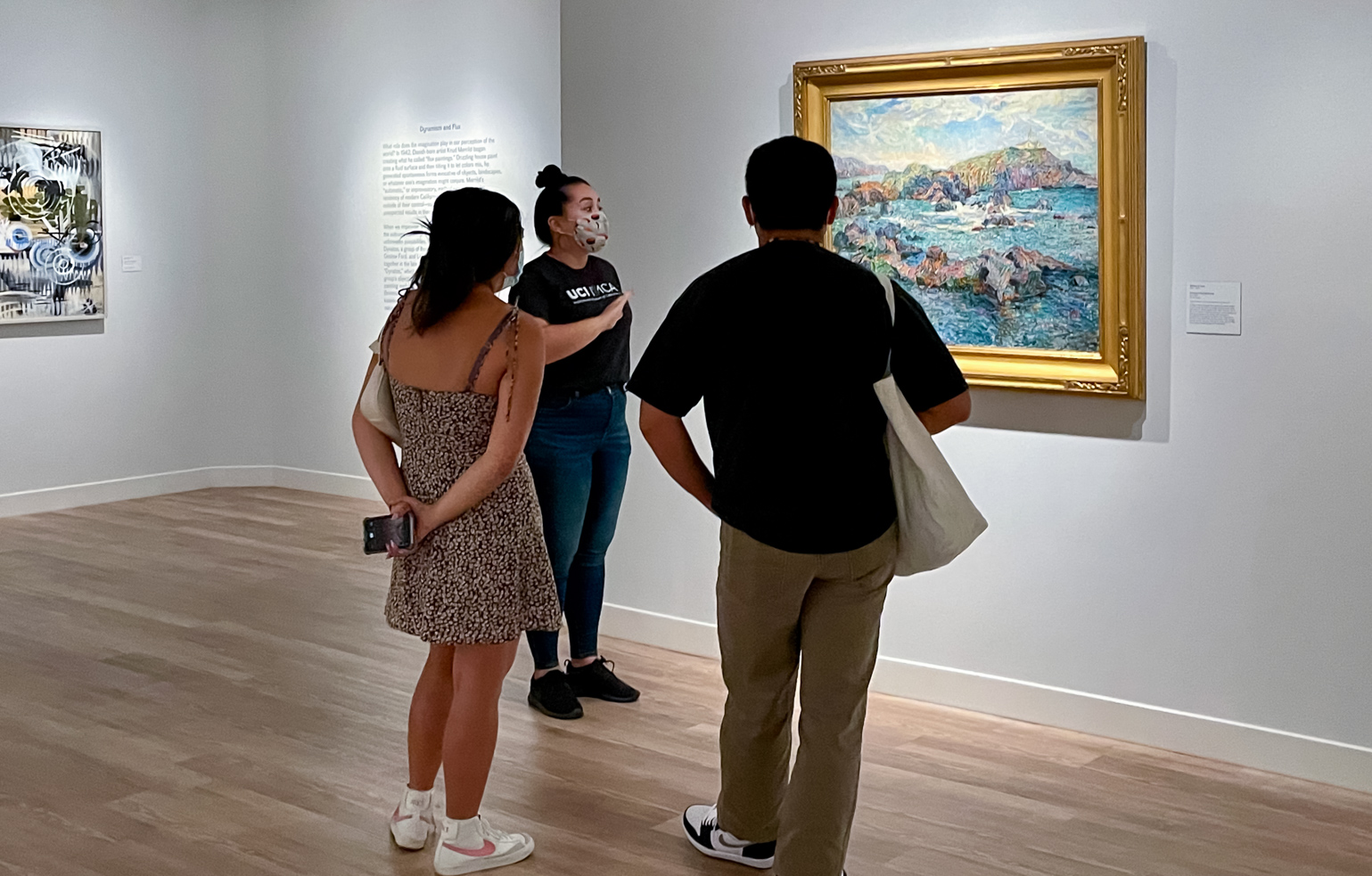 an IMCA gallery guide and two visitors discussing a painting in the museum