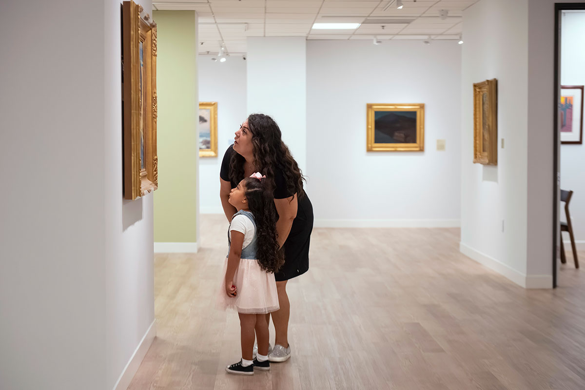 Mother and daughter patrons view a painting on exhibit